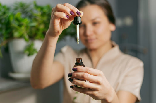 Woman holding an amber dropper bottle near a sunny window, representing ImmunoCeutica vitamin D supplementation